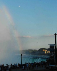 A photo of a rainbow at Niagara Falls with the 3/4 moon overhead.